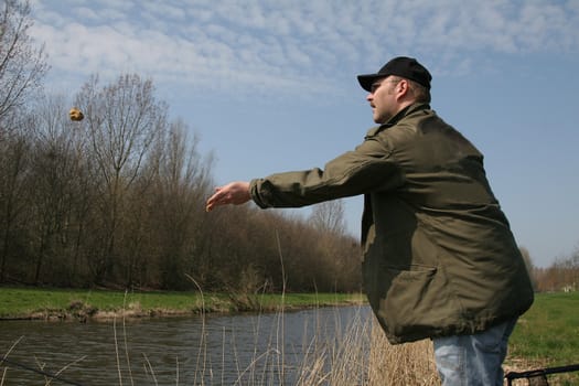 Fisherman throwing a feeding ball into the water