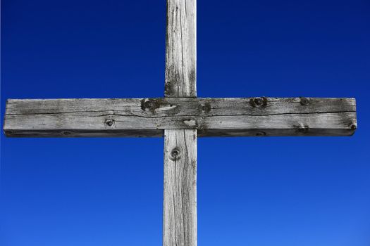 Part of a weathered wood cross on blue sky 