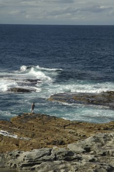 solitary fisherman on rocky coastline, photo taken near sydney