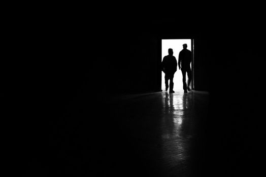 two man silhouettes entering a room, black and white photo