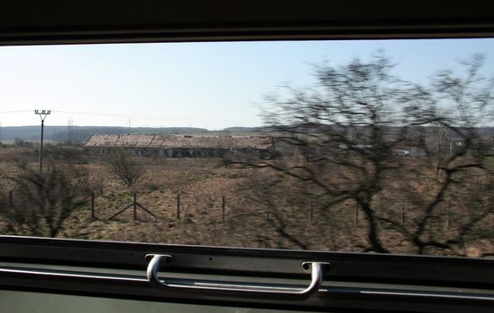looking through moving train window, farm in background