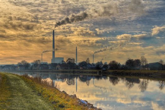View to a power plant across a channel with reflections from the surrounding houses and vegatation