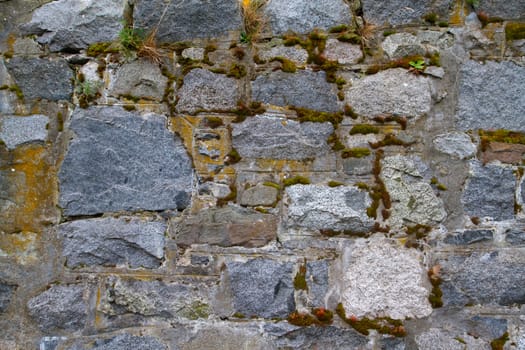 Several different moss covered rocks in a stone wall