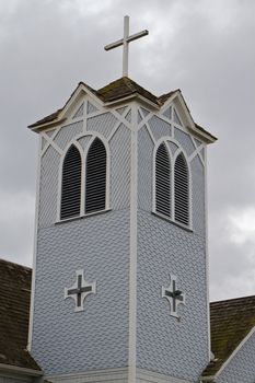 Gray and white wood church tower against a gloomy cloudscape