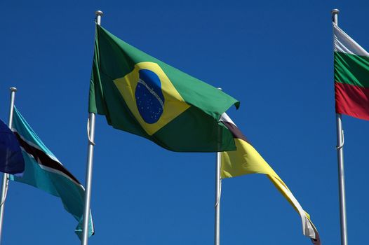 several flags on clear blue sky, brazilian flag in the middle