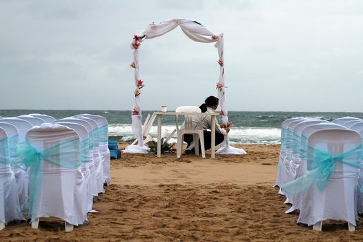 young woman preparing beach wedding, white decorated chairs