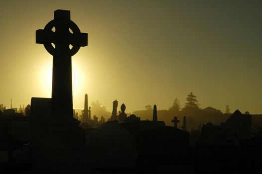 dusk at cemetery, black and yellow tonality, cross in foreground