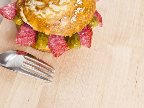 german bread roll with salami slices on a wooden plate