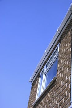 guttering and window on the front of a house against the blue sky
