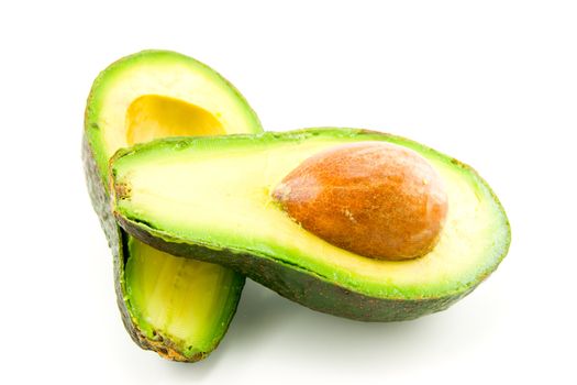 single dark green avocado fruit split in half and showing the kernel on a white background