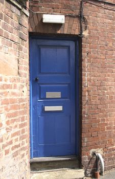 blue door in a old brick wall with a light above