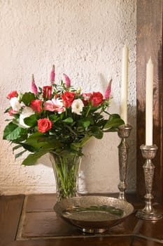 Classic stillife with silver candles, bowl and vase with flowers in red, white and pink