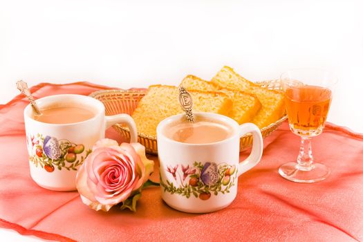 Two mugs of coffee with cake and a glass of amaretto liqueur