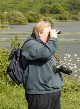 man persuing a leisurely pastime of bird spotting in a nature reserve
