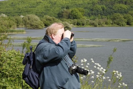 man persuing a leisurely pastime of bird spotting in a nature reserve