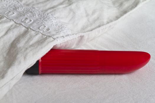 Red vibrator partly hidden under blanket