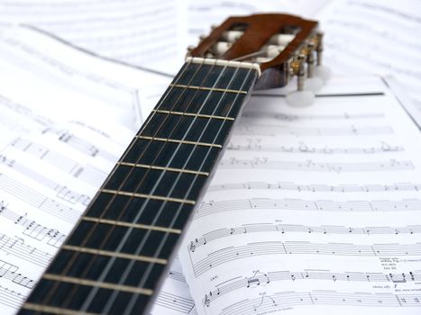 Acoustic guitar head and neck over sheet music