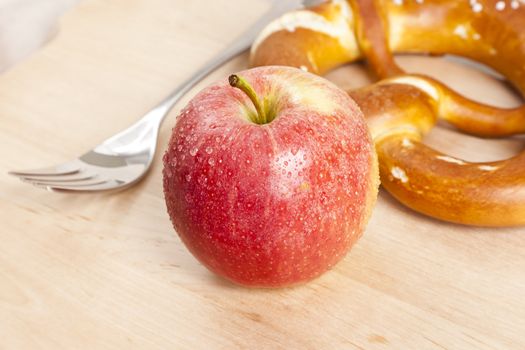 An image of a nice apple with fork and pretzel