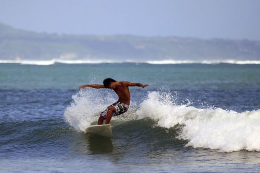 Young men - the surfer in ocean. Bali. Indonesia