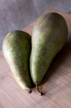Two fresh pears on cutting board.