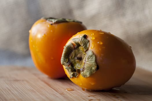 Two fresh persimmons on cutting board.