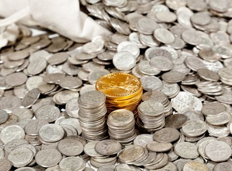 Linen bag of old pure silver coins used to invest in silver as a commodity with a selection of Golden Eagle gold coins