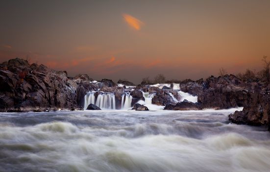 Waterfalls on the Potomac river near Washington DC after sunset as the setting sun illuminates the clouds over Great Falls