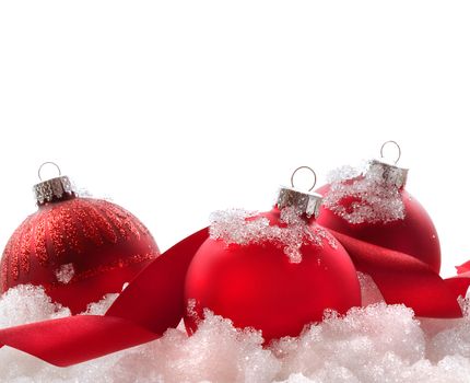 Red christmas balls and ribbon in snow on white background