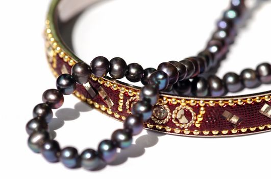 golden bangle and black pearl necklace on white