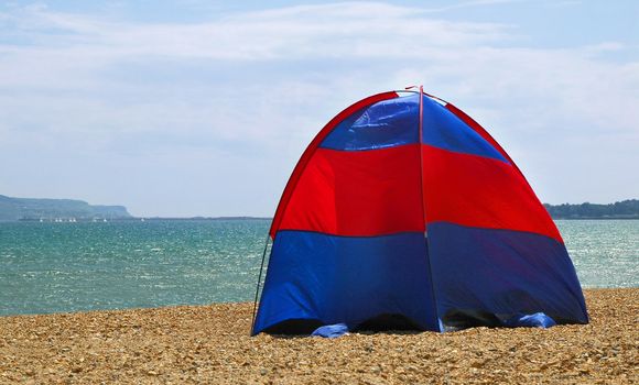 tent pitched on a stony beach (bay is weymouth bay, venue of the 2012 olympic sailing regatta)