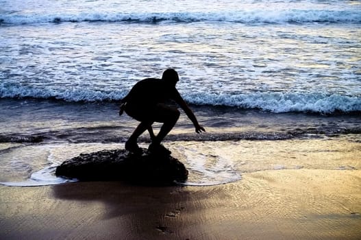 Silhouette of a young man looking to the sunset ocean