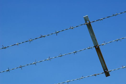 barbed wire fencing against blue sky