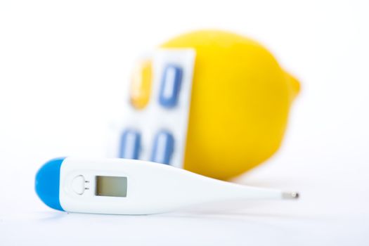 Thermometer, lemons and pills representing illness over white. Shallow dof.