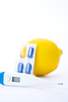 Thermometer, lemons and pills representing illness over white. Shallow dof.