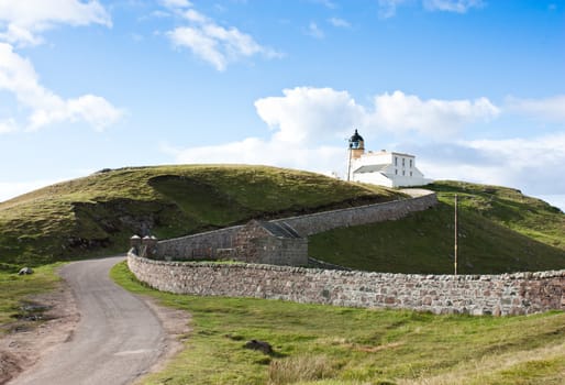 Tipical panorama of Scotland, with a lighthouse and blue sky