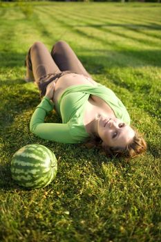 beautiful pregnantt woman on grass in park with watermelon