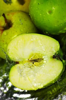 fresh water splash on green apple on metal background