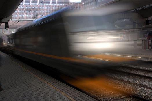 Speed blurred photo of train passing a paved station