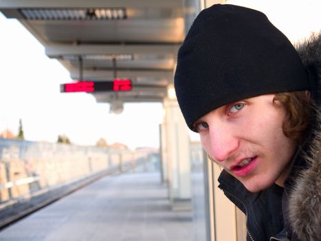 Sad young teen waiting for train with copy space