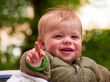 Happy baby boy laughing with joy and pointing