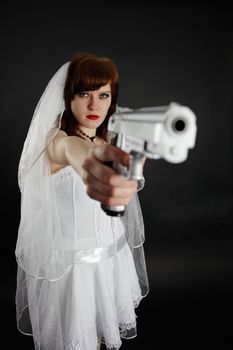 Serious bride take aim with a big pistol on black background