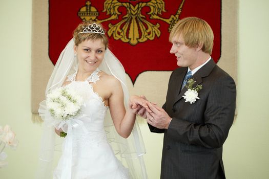 The groom solemnly puts the ring on the bride