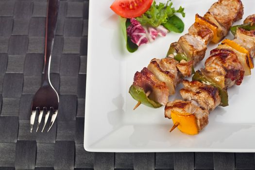 shashlik on a plate with a tomato and salad leaf