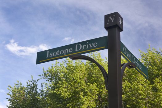 Isotope and Oval Drive - street sign on Colrado State University Campus at Fort Collins against blue sky and fresh green tree leaves