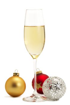 glass of champagne with golden, red and metal christmas balls on white background