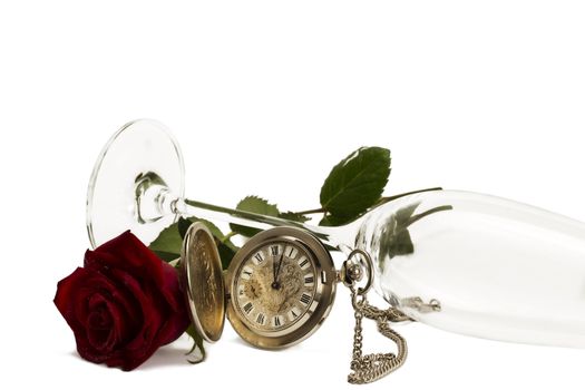 old pocket watch with a red wet rose under a lying champagne glass on white background