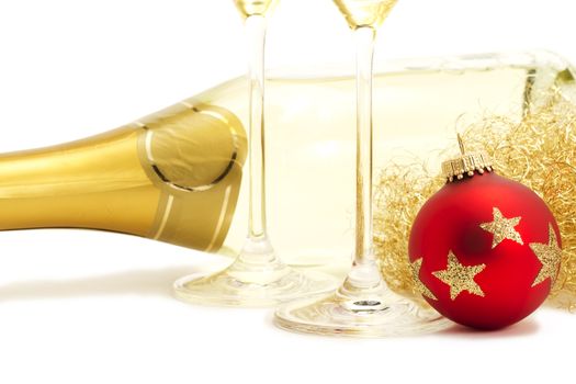 red christmas ball in front of angels hair, two champagne glasses bottoms and a champagne bottle on white background