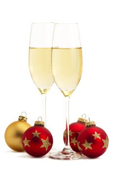 two glasses with champagne with one golden and three red christmas balls on white background