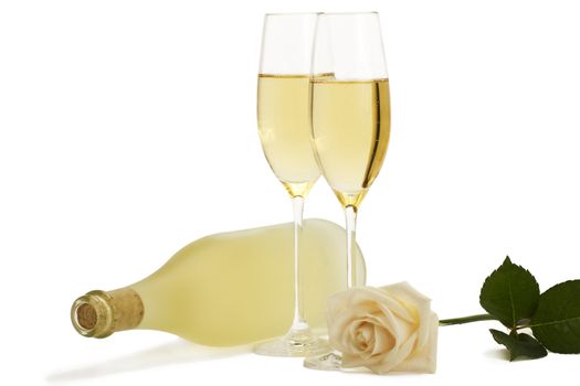 creamy rose in front of two champagne glasses and a dull prosecco bottle on white background