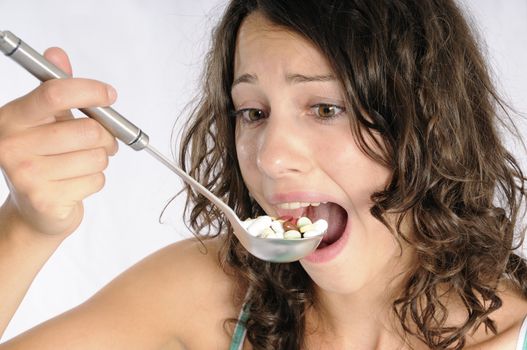 Shot of cute girl with spoon full of pills. Concept shot for alternative medicine